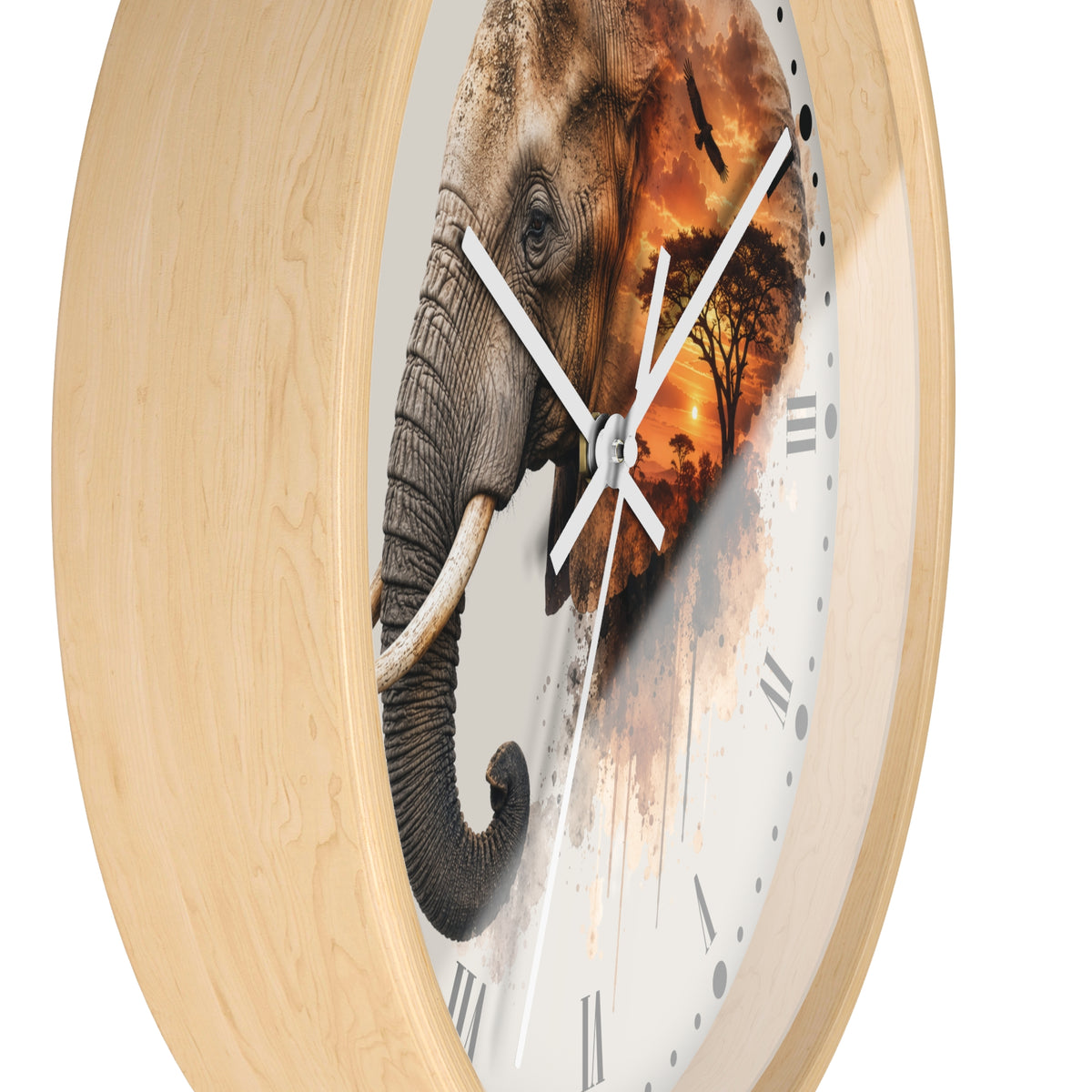 Round wall clock with a light natural wood frame and a white dial featuring a split elephant design, with one half showing a gray elephant and the other half blending into an orange savanna sunset scene.