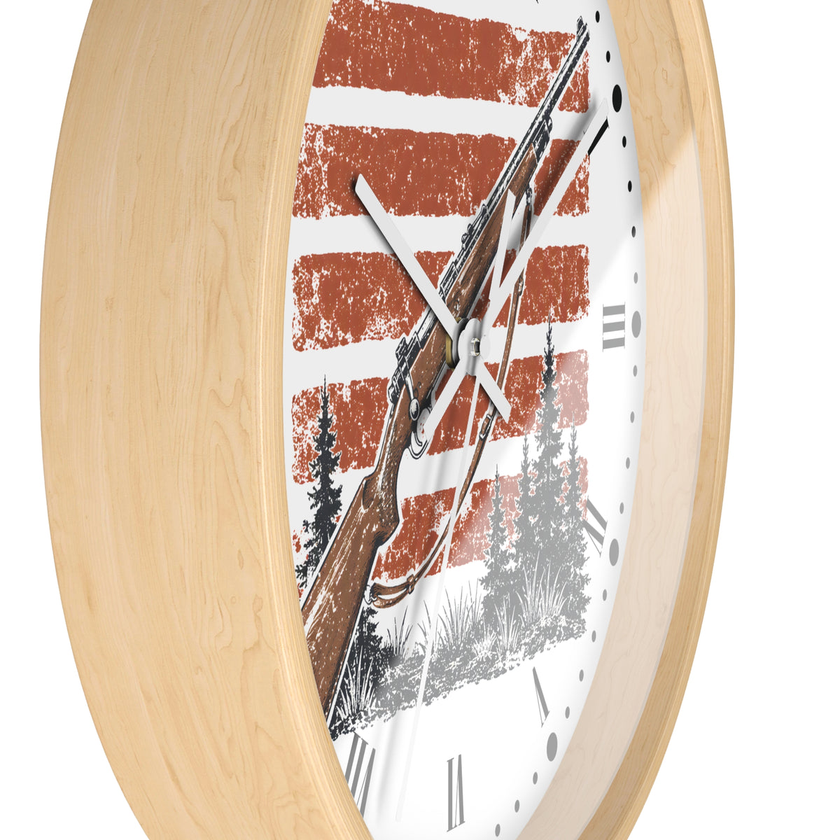 A close-up of a round wall clock with a light natural wood frame and a white face featuring a rustic red-and-white striped background, a brown rifle illustration, and black tree silhouettes. Roman numerals mark the hours.