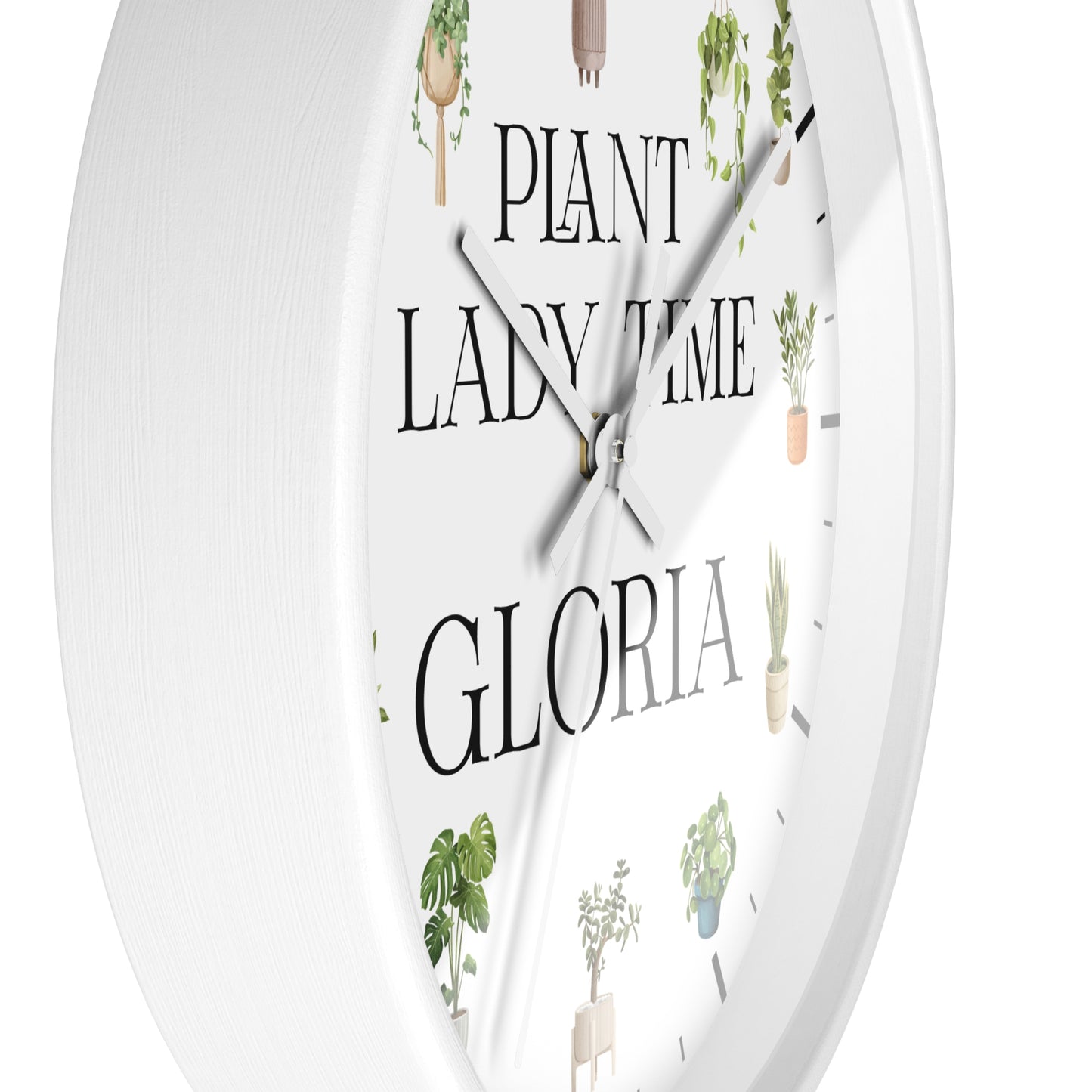 A white round wall clock with a minimalist design, featuring the text 'PLANT LADY TIME GLORIA' in black serif font and delicate illustrations of potted green plants around the dial.