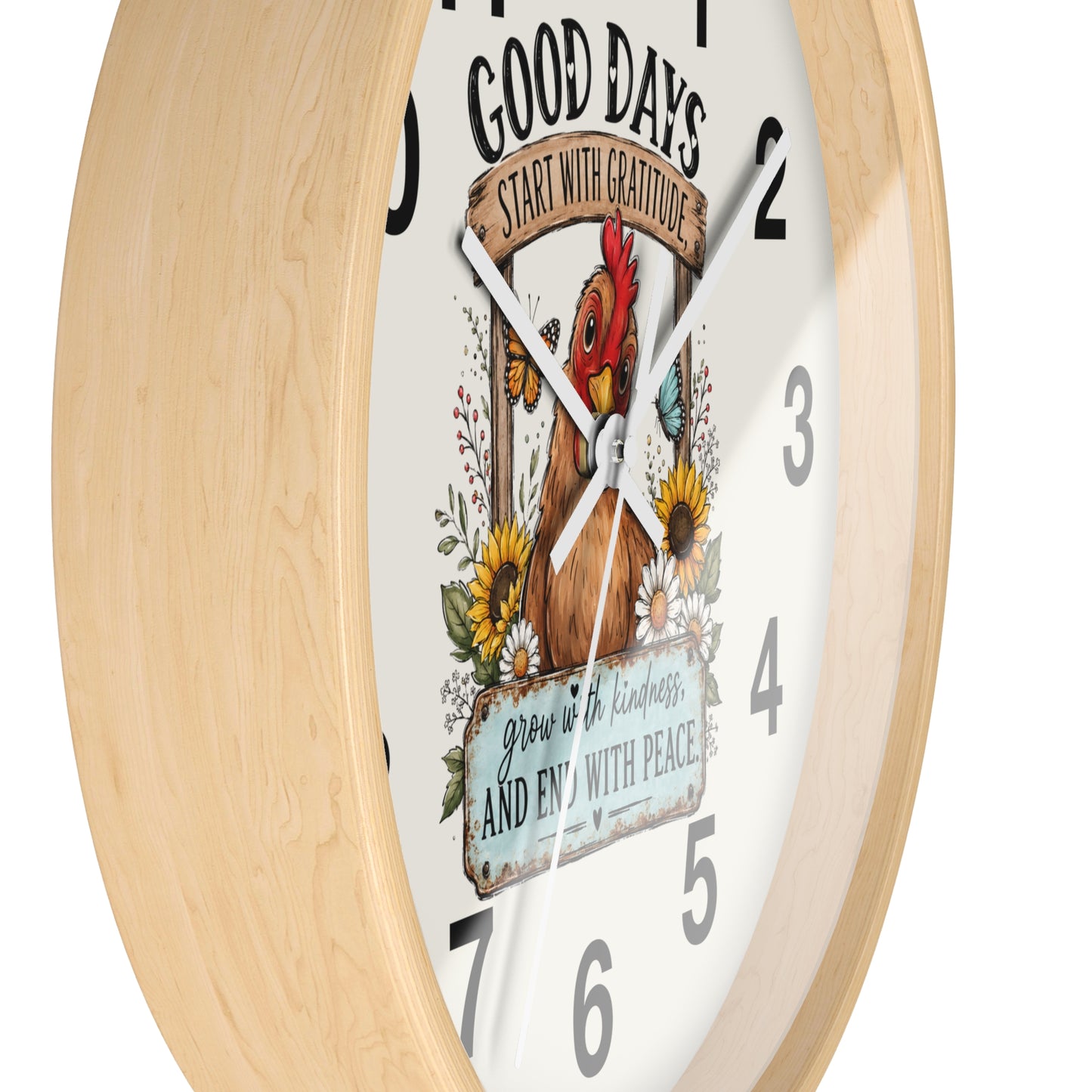 A round wall clock with a light natural wood frame and a white face featuring a colorful illustration of a rooster, flowers, and the text 'GOOD DAYS START WITH GRATITUDE' and 'grow in kindness and end with peace.'.