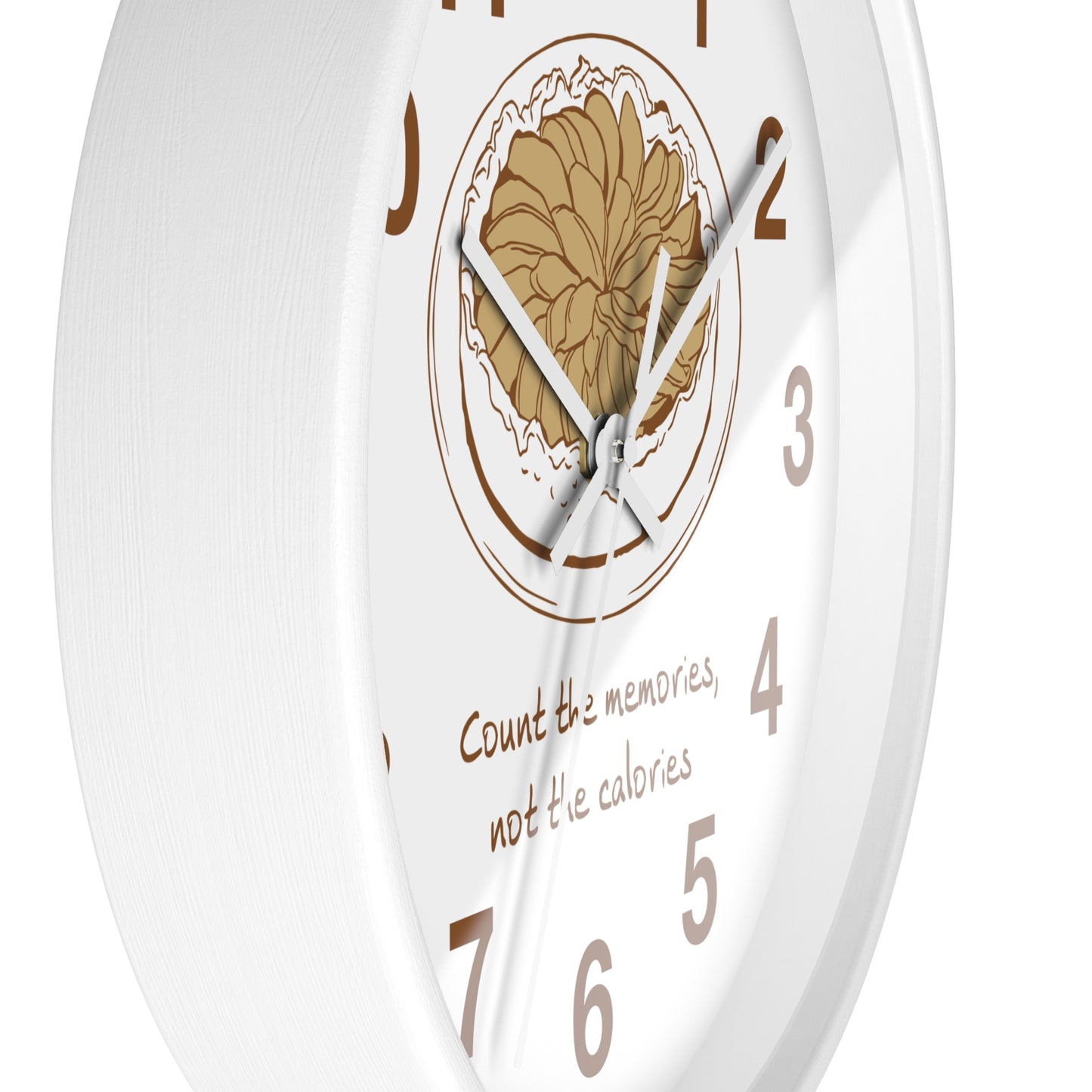 A white round wall clock with a central floral illustration in tan and brown, silver hands, brown numerals, and the phrase 'Count the memories, not the calories' printed near the bottom.