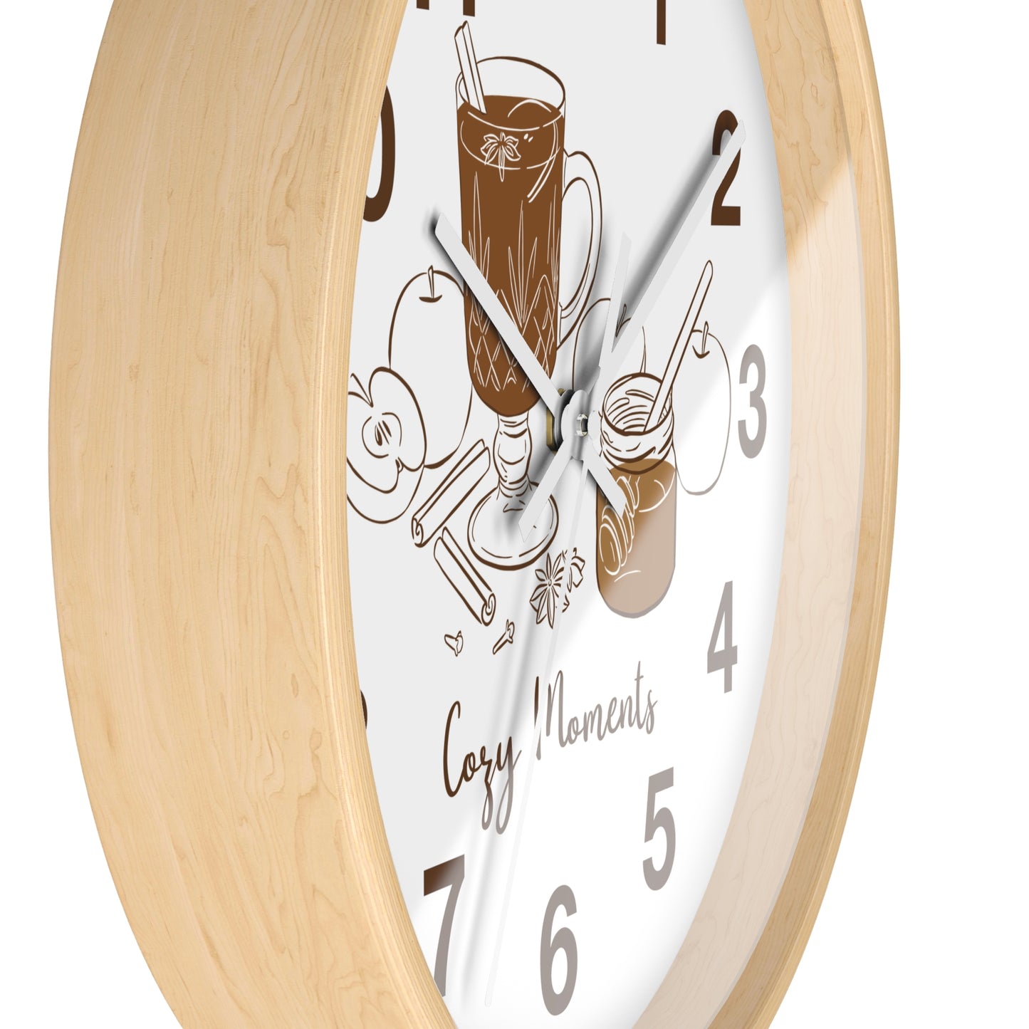 A close-up of a wall clock with a light natural wood frame and a white face featuring brown coffee-themed illustrations and the words 'Cozy Moments'.