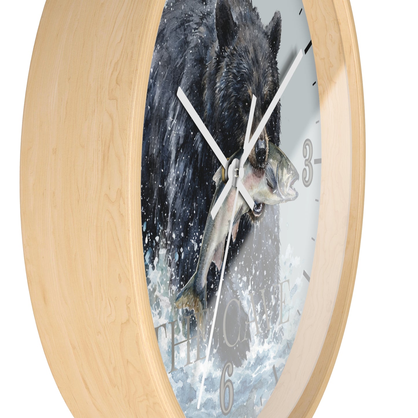 A round wall clock with a light natural wood frame and a printed face showing a black bear catching a fish in splashing water, photographed against a plain white background.