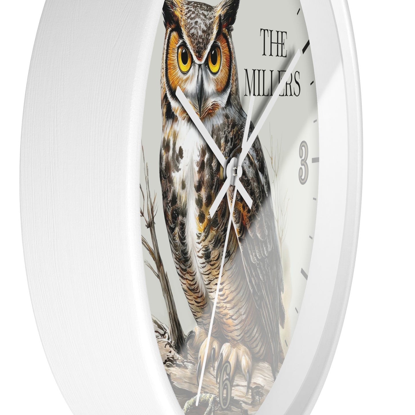 A white round wall clock featuring a detailed illustration of a great horned owl on the face, with black hands, black hour markers, and the text 'THE MILLERS' near the top right.