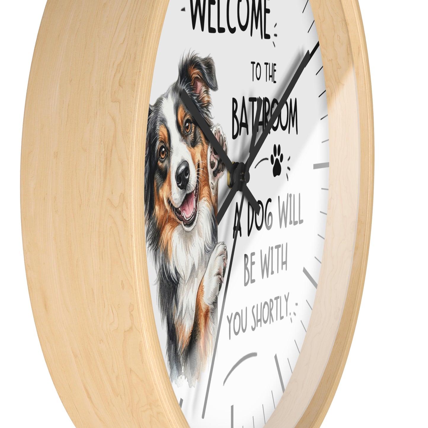Round wall clock with a light natural wood frame and a white face featuring an illustration of a smiling dog and the text 'WELCOME TO THE BATROOM A DOG WILL BE WITH YOU SHORTLY'.