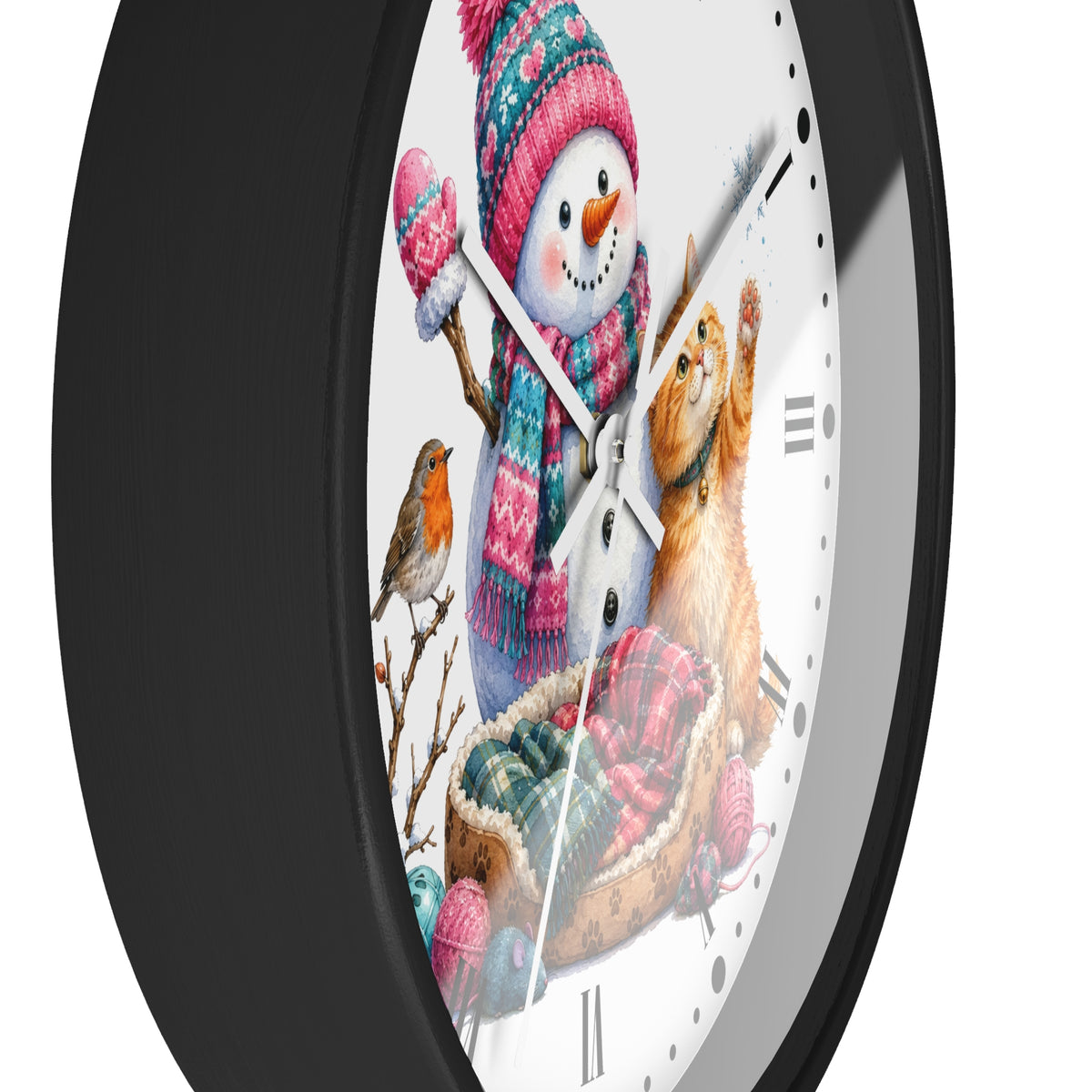 A round wall clock with a black frame and a white face featuring a festive winter illustration of a snowman, a ginger cat in a basket, a small bird, and knitted yarn balls.