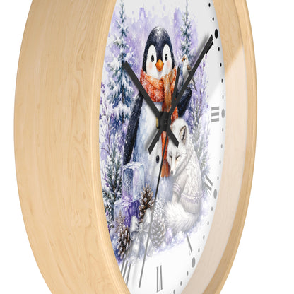 A round wall clock with a light natural wood frame and a white face featuring a winter illustration of a penguin, fox, pine trees, and snow.