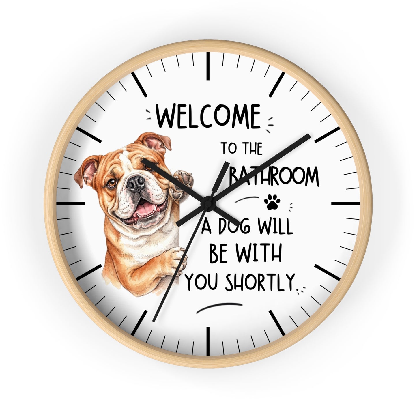 A round wall clock with a light wood frame and a white face, featuring a brown and white bulldog illustration and the text 'WELCOME TO THE BATHROOM A DOG WILL BE WITH YOU SHORTLY.' on a plain white background.