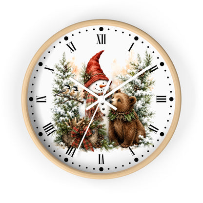 A round wall clock with a light wood frame and a white face featuring a winter holiday illustration of a snowman in a red hat, a brown bear, evergreen trees, and black Roman numerals.