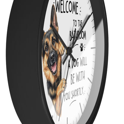 A round wall clock with a black frame and a white face featuring a German Shepherd illustration and the text 'WELCOME TO THE BATHROOM A DOG WILL BE WITH YOU SHORTLY.