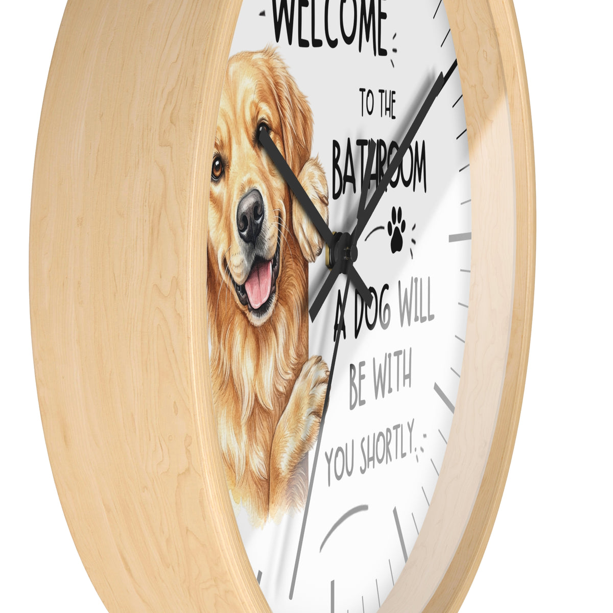 A round wall clock with a light natural wood frame and a white face featuring a golden retriever illustration and the text 'WELCOME TO THE BATROOM A DOG WILL BE WITH YOU SHORTLY'.