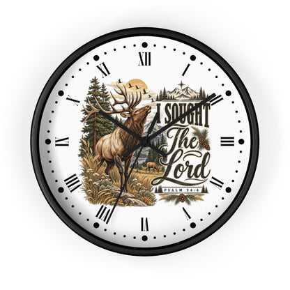 A round wall clock with a black frame and a white face featuring a detailed illustration of a deer in a forest, mountains, and the text 'I SOUGHT The Lord Psalm 34:5'.