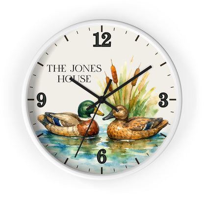 A round wall clock with a white frame and a printed watercolor-style design featuring two ducks on water, cattails, and the text 'THE JONES HOUSE' on the clock face.