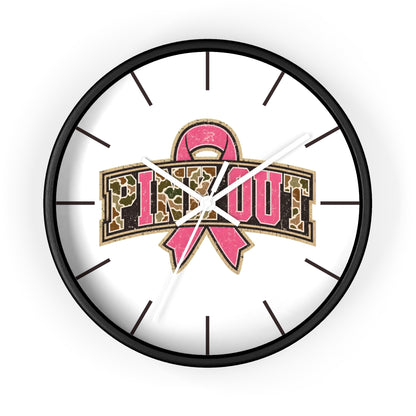 A round wall clock with a black frame and a white face, featuring a pink ribbon and the words 'PINE OUT' in leopard-print lettering. The clock is shown against a plain white background.