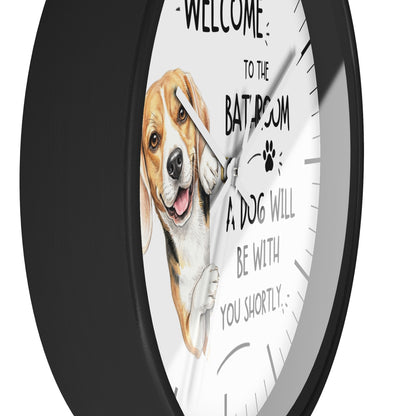 A round wall clock with a black frame and a white face, featuring a painted beagle illustration and the text 'WELCOME TO THE BATHROOM A DOG WILL BE WITH YOU SHORTLY'.