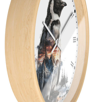 Round wall clock with a light natural wood frame and a white face featuring a printed penguin and mountain landscape design.