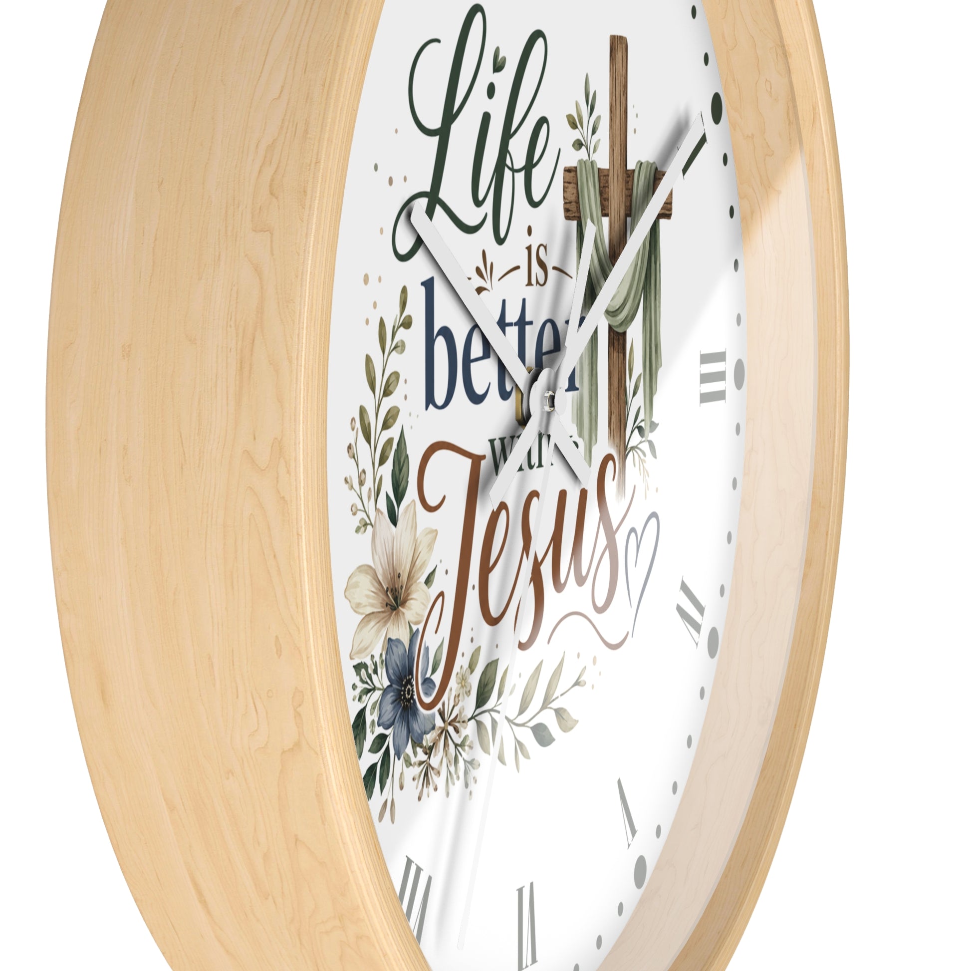A round wall clock with a light natural wood frame and a white face featuring the phrase 'Life is better with Jesus' in decorative script and floral illustrations.