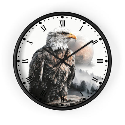 A round wall clock with a black frame and a printed design featuring a bald eagle in front of a misty mountain landscape and a large moon. The clock face is white with black Roman numerals and black hands.