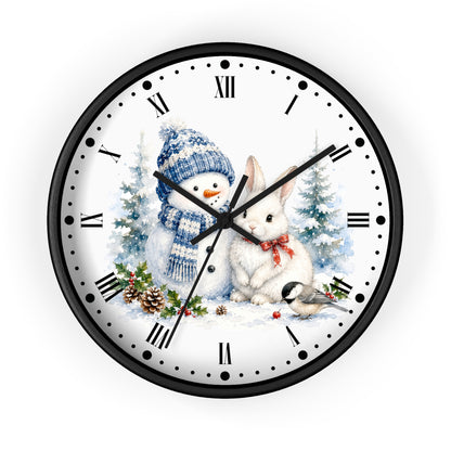 A round wall clock with a black frame and a white face featuring a winter holiday illustration of a snowman in a blue knit hat, a white rabbit with a red bow, evergreen trees, pinecones, and a small bird. The clock uses Roman numerals and black hands.