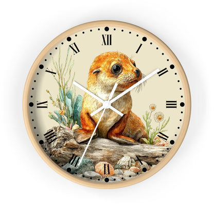 A round wall clock with a light wood frame and a cream-colored face, featuring an illustration of a brown seal pup sitting on driftwood with plants and shells. The clock has black Roman numerals and white hands.