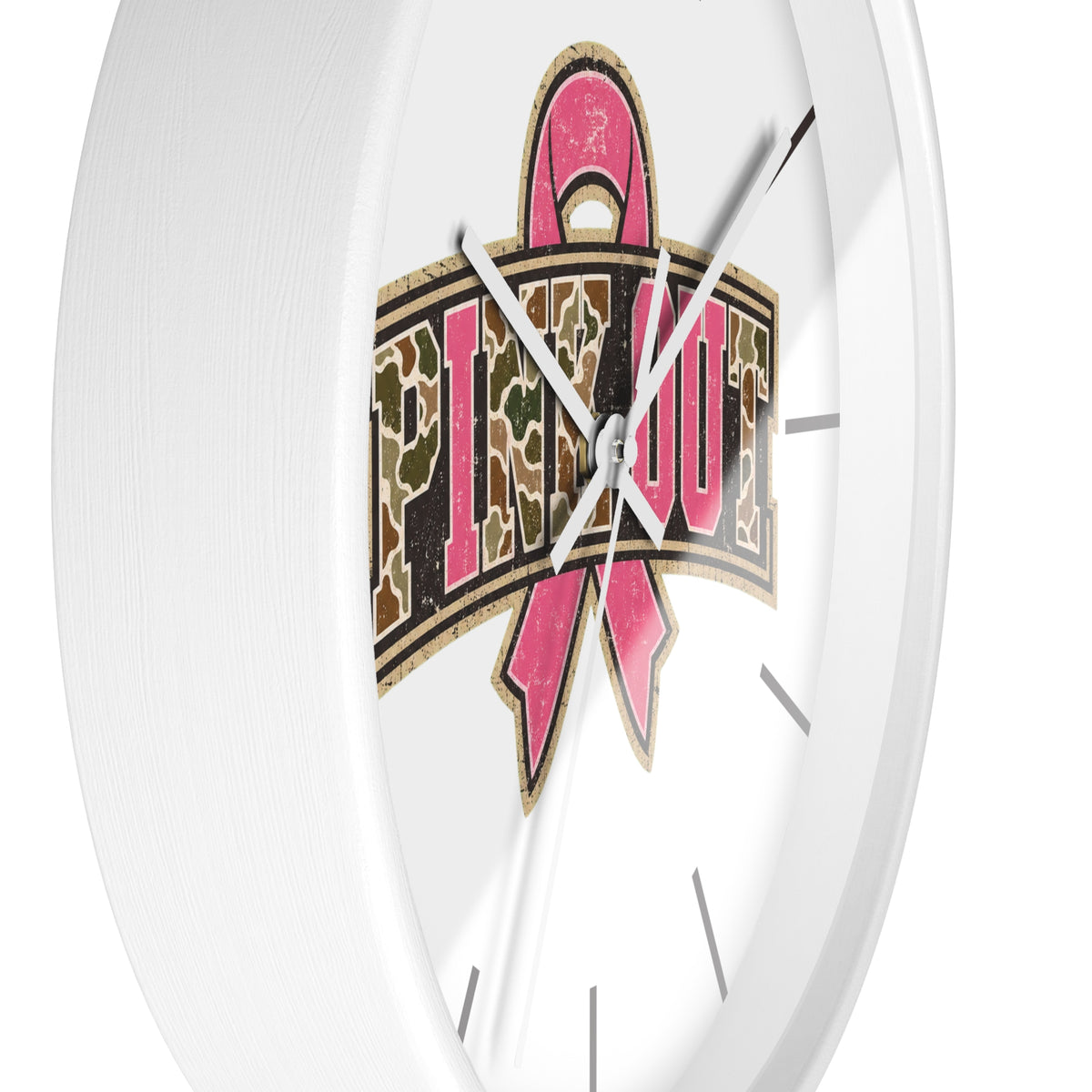 A close-up of a white wall clock face featuring a large pink ribbon and the word 'PIMP OUT' in a camouflage pattern, with silver hands against a clean white background.