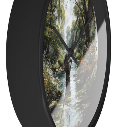 Round wall clock with a black frame and a printed scenic design of a person walking through a shallow stream in a forest, shown against a white background.