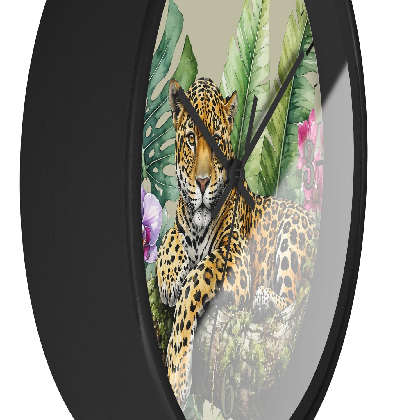 Round wall clock with a black frame and tropical jungle print featuring a leopard, large green leaves, and pink flowers on a light beige background.
