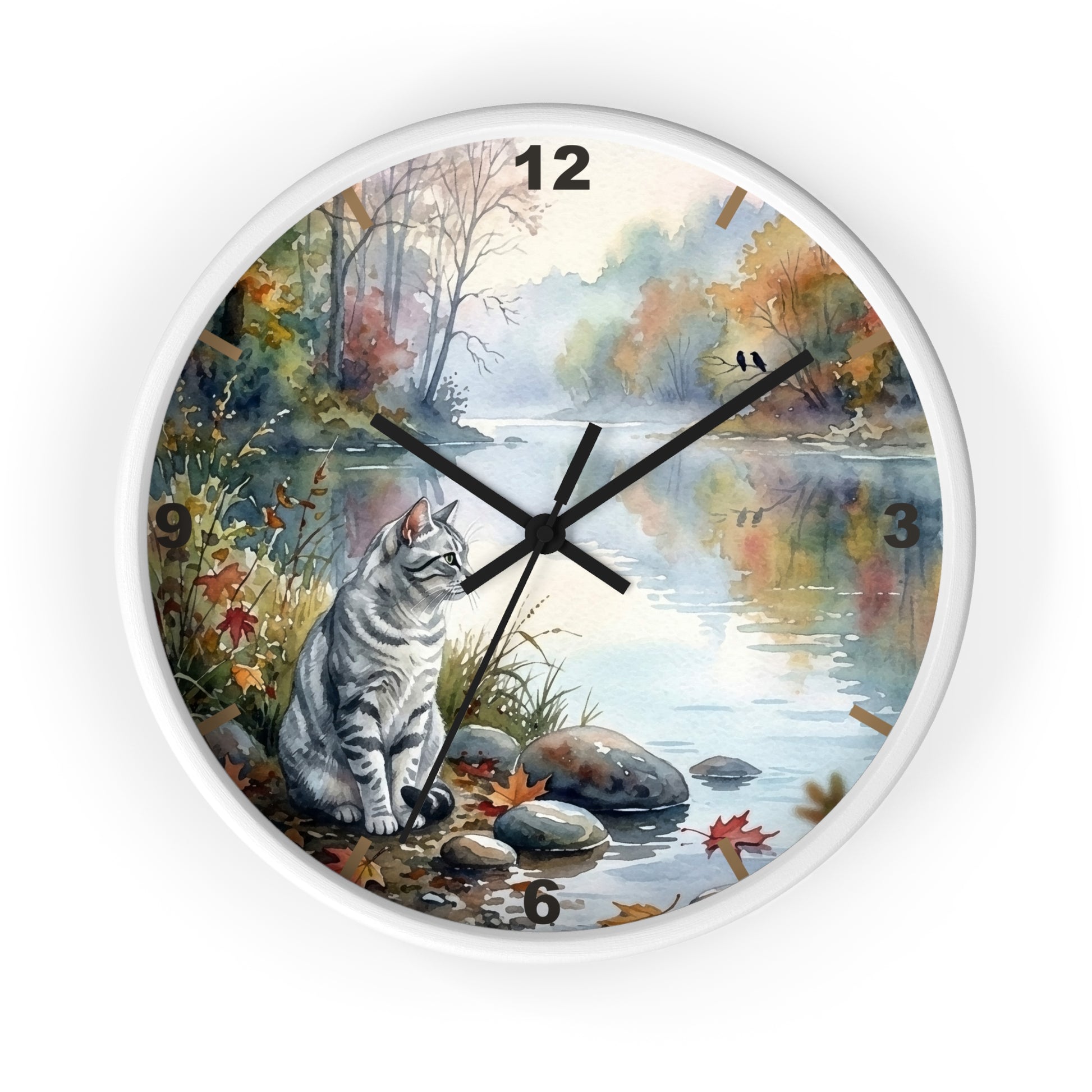 Round wall clock with a white frame and a printed scenic design featuring a gray tabby cat sitting by a river in autumn foliage. The clock face includes black Arabic numerals and black hands, shown against a plain white background.