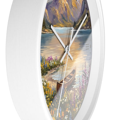 A white oval wall clock with a scenic landscape print on the face, showing a lake, mountains, flowers, and a canoe. The clock has white hands and is photographed against a plain white background.