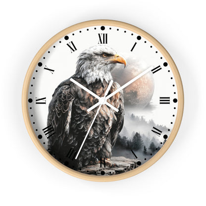A round wall clock with a light wood frame and a printed dial featuring a large bald eagle over a misty forest and moon. The clock has black Roman numerals, black dot hour markers, and white hands, shown on a plain white background.