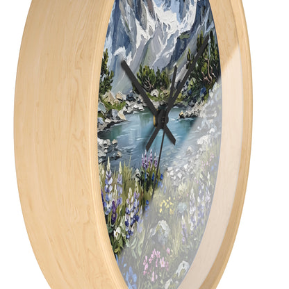 Oval wall clock with a light natural wood frame and a scenic mountain lake painting in the center, featuring black clock hands.