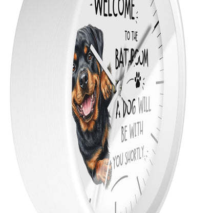 A white round wall clock with a printed Rottweiler dog graphic and the text 'WELCOME TO THE BATROOM A DOG WILL BE WITH YOU SHORTLY' on the dial.