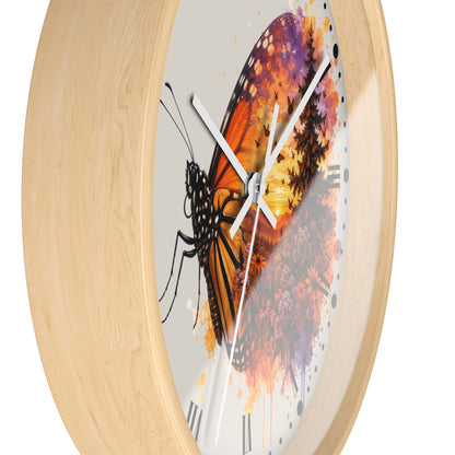 Round wall clock with a light natural wood frame and a white dial featuring a large orange, black, and purple butterfly illustration over a floral watercolor background.