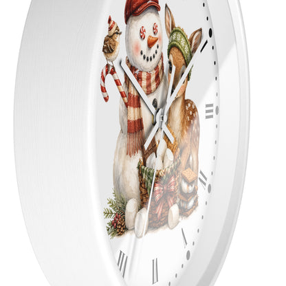 A round white wall clock with a festive winter illustration featuring a snowman in a red hat and scarf, a small bird, and a deer wearing a green knit hat, set against a clean white background.