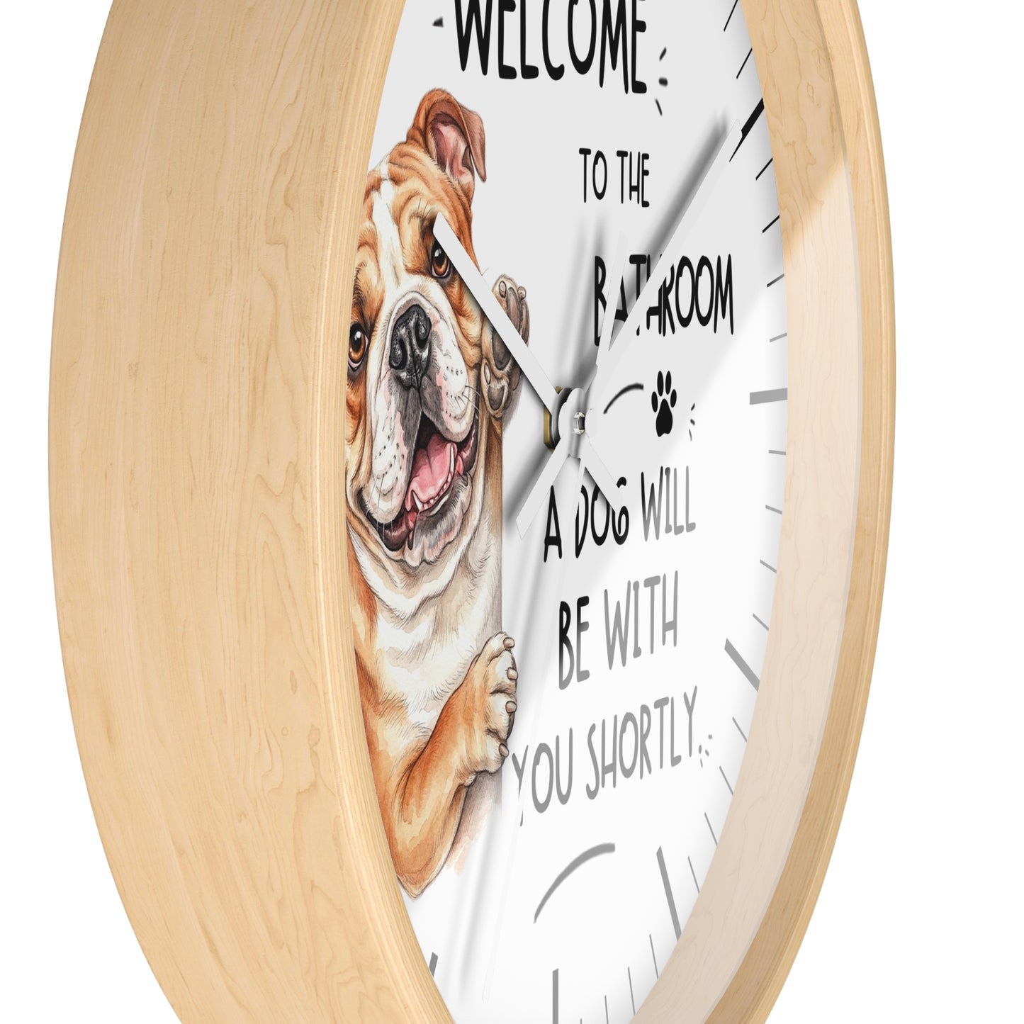 A round wall clock with a light natural wood frame and a white face featuring a cartoon bulldog and the text 'WELCOME TO THE BATHROOM A DOG WILL BE WITH YOU SHORTLY'.