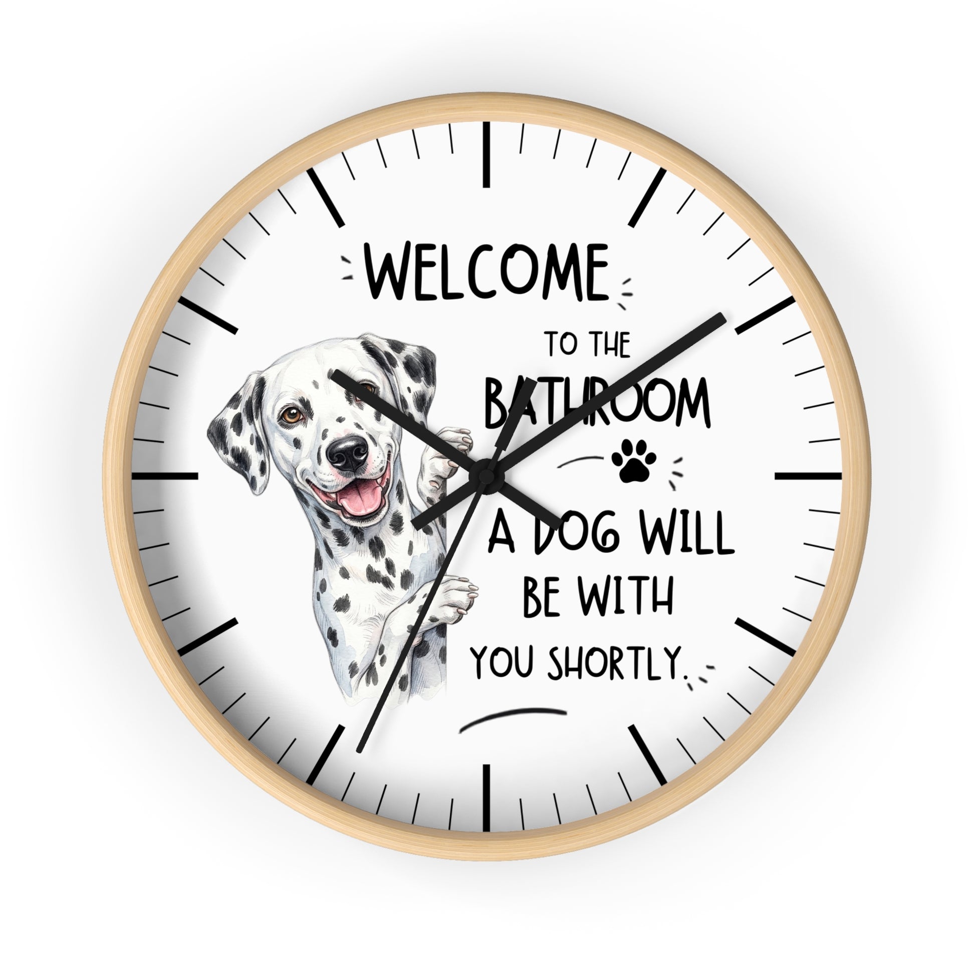 A round wall clock with a light wood frame and a white face, featuring a Dalmatian illustration and the text 'WELCOME TO THE BATHROOM A DOG WILL BE WITH YOU SHORTLY.' on a plain white background.