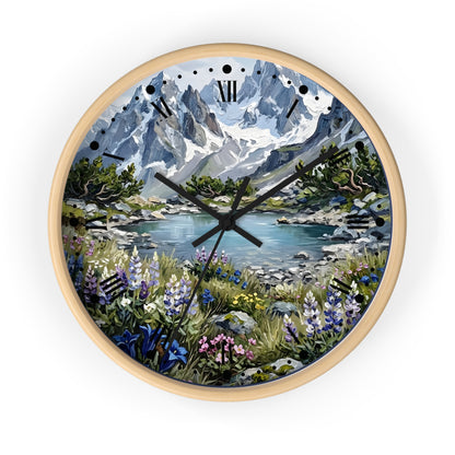 A round wall clock with a light natural wood frame, featuring a scenic landscape print of snow-capped mountains, a lake, and wildflowers on the clock face.