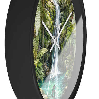 A round wall clock with a black frame and a printed scenic dial showing a lush green waterfall in a tropical forest, photographed against a plain white background.