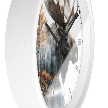 A round wall clock with a white frame and a printed design featuring a moose head over a misty forest scene with autumn trees. The clock is shown at an angle against a plain white background.