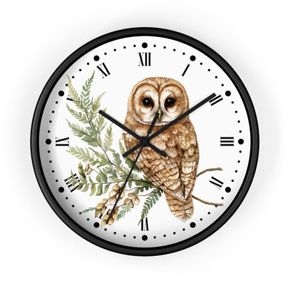 A round wall clock with a black frame and a white face, featuring a detailed illustration of a brown owl perched on a green fern branch. The clock uses black Roman numerals and black hands.
