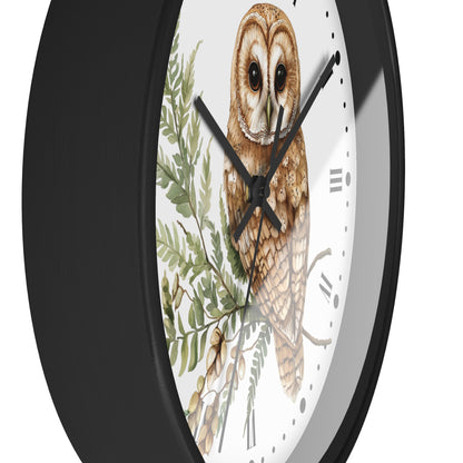 A close-up of a round wall clock with a black frame and a white face featuring a detailed illustration of a brown barn owl over green leaves.