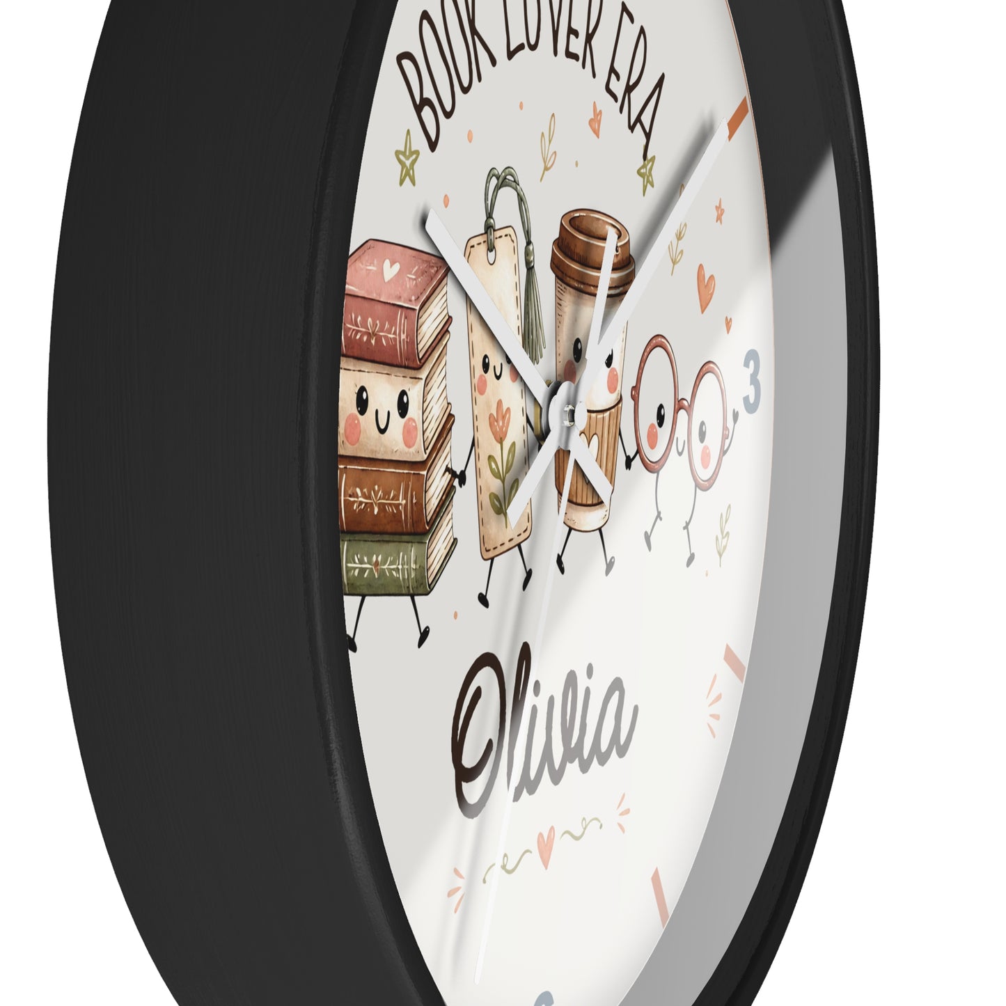 A round wall clock with a black frame and a white face featuring cute illustrated books, a coffee cup, glasses, and the text 'BOOK LOVER ERA' and 'Olivia'.