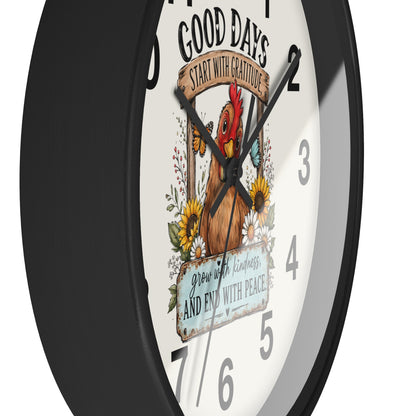 A close-up of a round wall clock with a black frame and a white face featuring a decorative rooster illustration, floral elements, and the text 'GOOD DAYS START WITH GRATITUDE' and 'grow with kindness AND END with PEACE'.