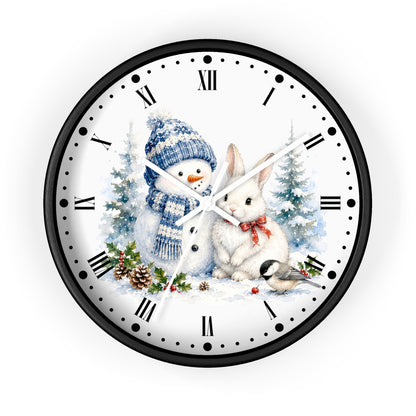 A round wall clock with a black frame and a white face featuring a winter holiday illustration of a snowman in a blue knit hat and scarf next to a white rabbit with a red bow tie, with pine trees and holly accents.