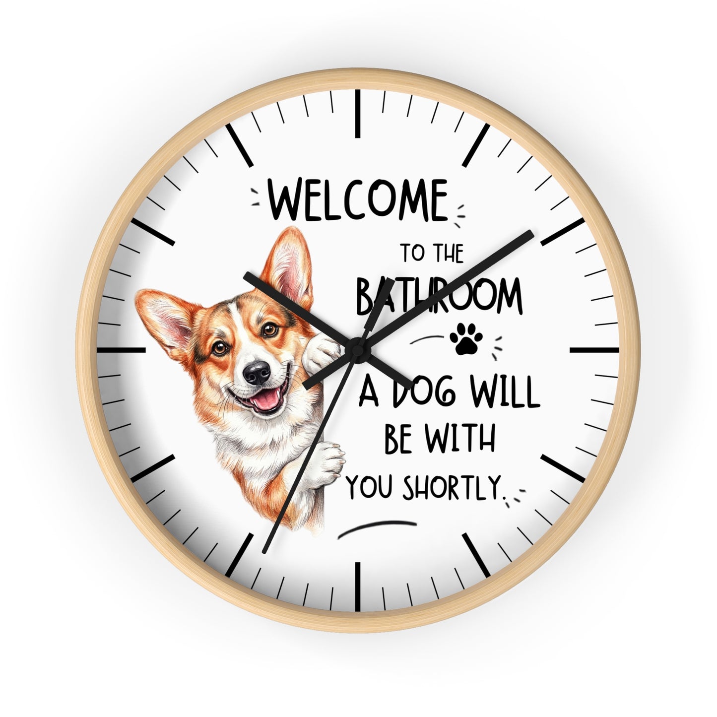 A round wall clock with a light wood frame and a white face, featuring a cartoon Corgi illustration and the text 'WELCOME TO THE BATHROOM A DOG WILL BE WITH YOU SHORTLY.' on a plain white background.