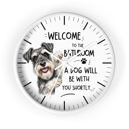 A round white wall clock with a printed illustration of a gray and white dog and the humorous text 'WELCOME TO THE BATHROOM A DOG WILL BE WITH YOU SHORTLY.' on a clean white background.