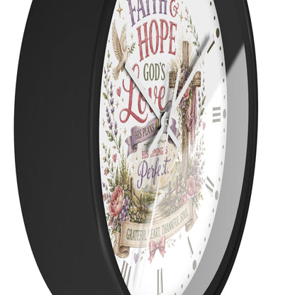 A round wall clock with a black frame and a white face featuring religious artwork and the words 'Faith & Hope God's Love His Plans His Timing is Perfect' with a cross, floral details, and Roman numerals.