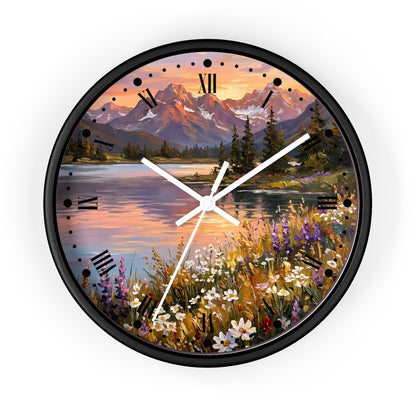A round wall clock with a black frame and a scenic landscape print featuring mountains, a lake, trees, and wildflowers. The clock face has black Roman numerals and white hands.
