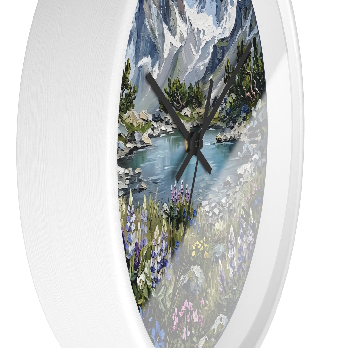 An oval wall clock with a white frame and a scenic landscape print featuring mountains, a river, trees, and wildflowers. The clock hands are black and visible against the light background.