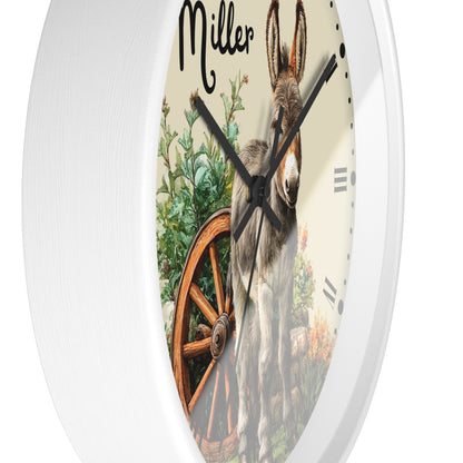 Round white wall clock with a printed front featuring a donkey, green plants, a wooden wagon wheel, and the name 'Miller' in script near the top.
